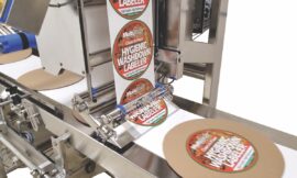 close up of hygienic washdown labeler machine labeling frozen pizza packaging